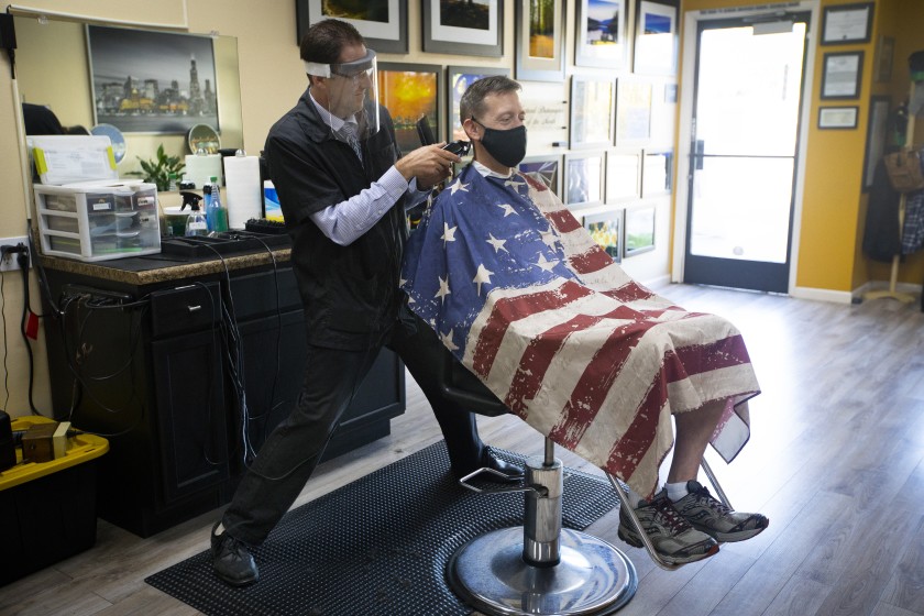 Dan Collins, co-owner of Skyline Barbershop in Temecula, cuts Gene Kelley’s hair on May 26, 2020, the first day they could open. (Francine Orr / Los Angeles Times)