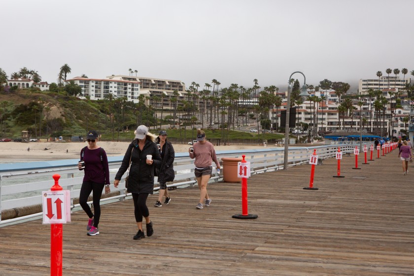 A group of women walk the San Clemente Pier on May 18, 2020. (Gabriella Angotti-Jones / Los Angeles Times)