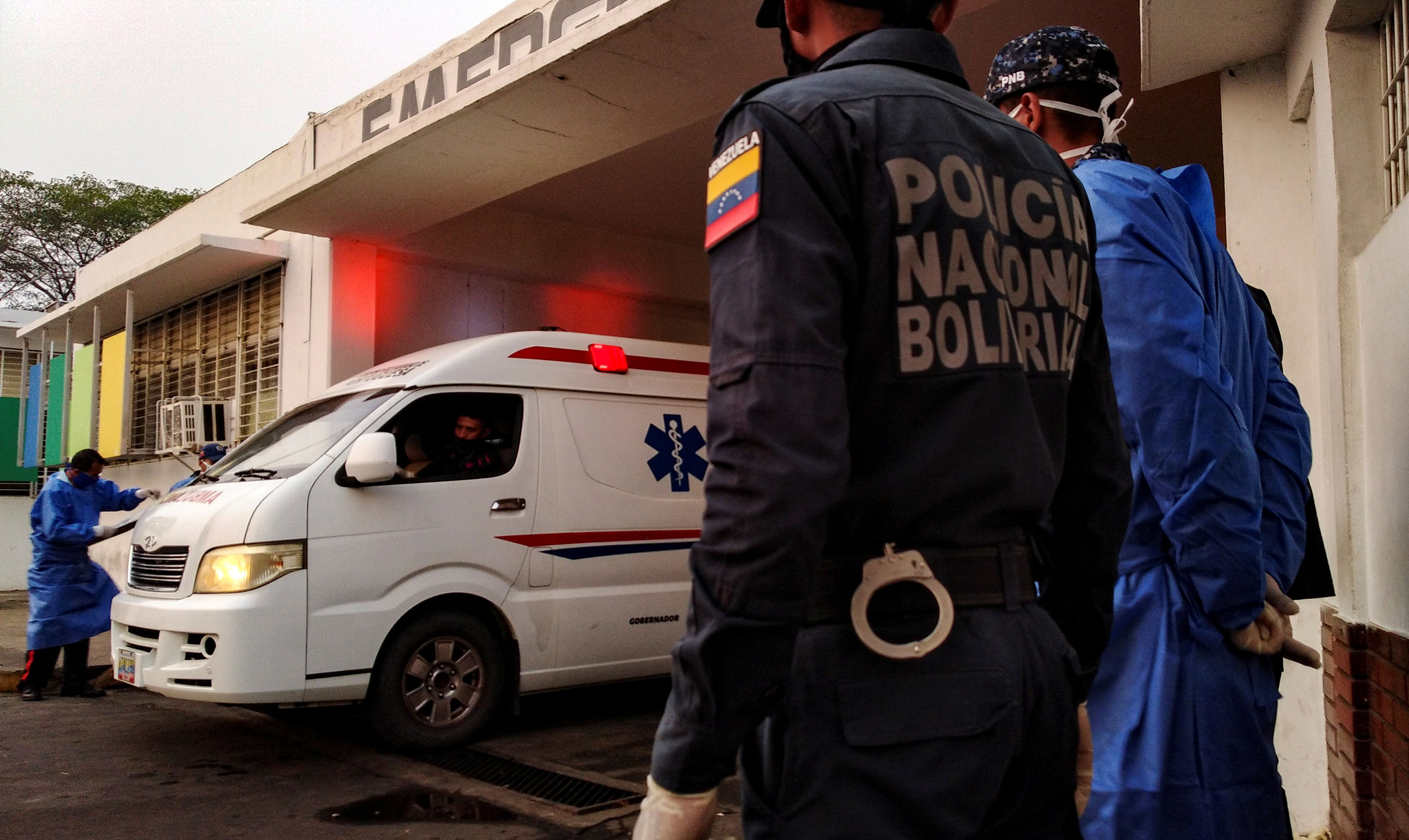 Healthcare workers and members of the Bolivarian national police watch as an ambulance arrives with prisoners outside a hospital after a riot erupted inside a prison in Guanare, Venezuela May 1, 2020. (REUTERS/Manuel Alvarado via CNN)