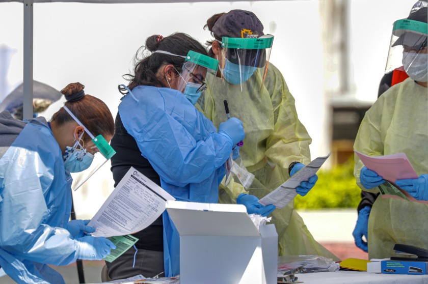 San Bernardino County Department of Public Health workers collect coronavirus samples at a drive-through testing site in Montclair in this undated photo. (Irfan Khan / Los Angeles Times)