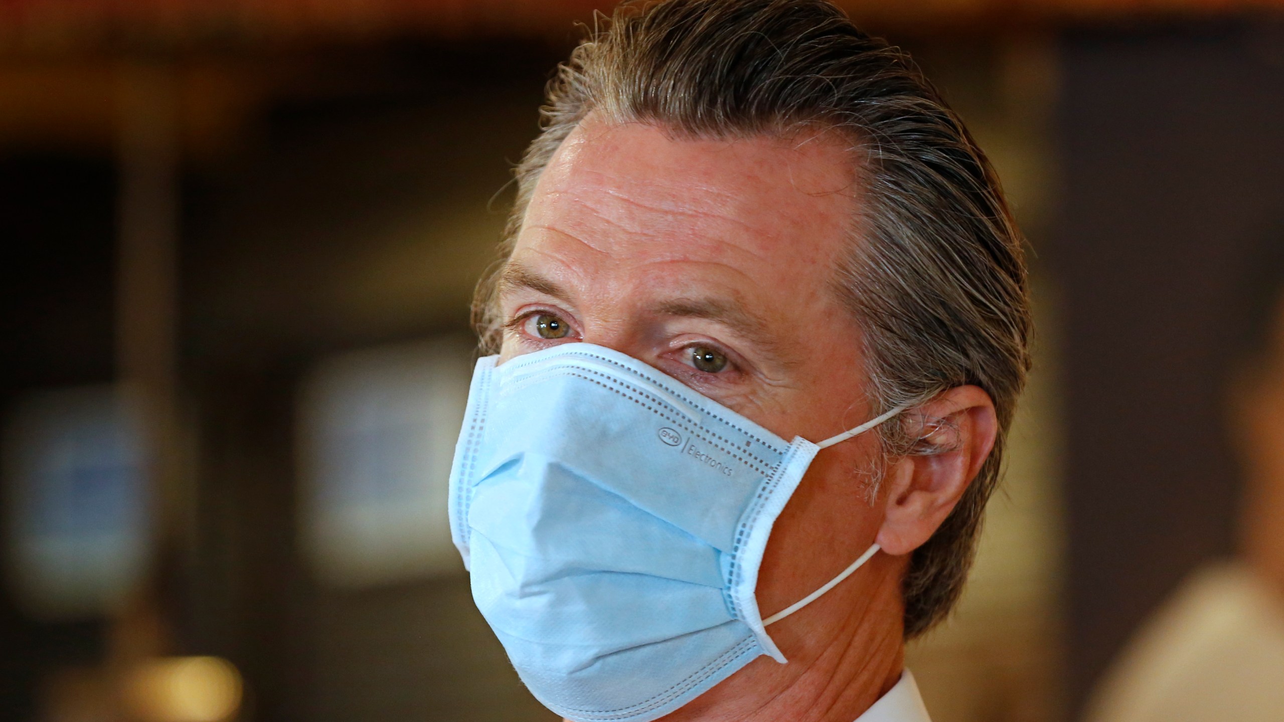 In this June 19, 2020, file photo, California Gov. Gavin Newsom, wears a face mask as he answers a reporter's question during his visit to the Queen Sheba Ethiopian Cuisine restaurant in Sacramento, Calif. Newsom implored people Monday, June 22, 2020, to wear face coverings to protect against the coronavirus and allow businesses to safely open after several days in which the state saw its highest virus hospitalizations and number of infections to date. (AP Photo/Rich Pedroncelli, Pool)