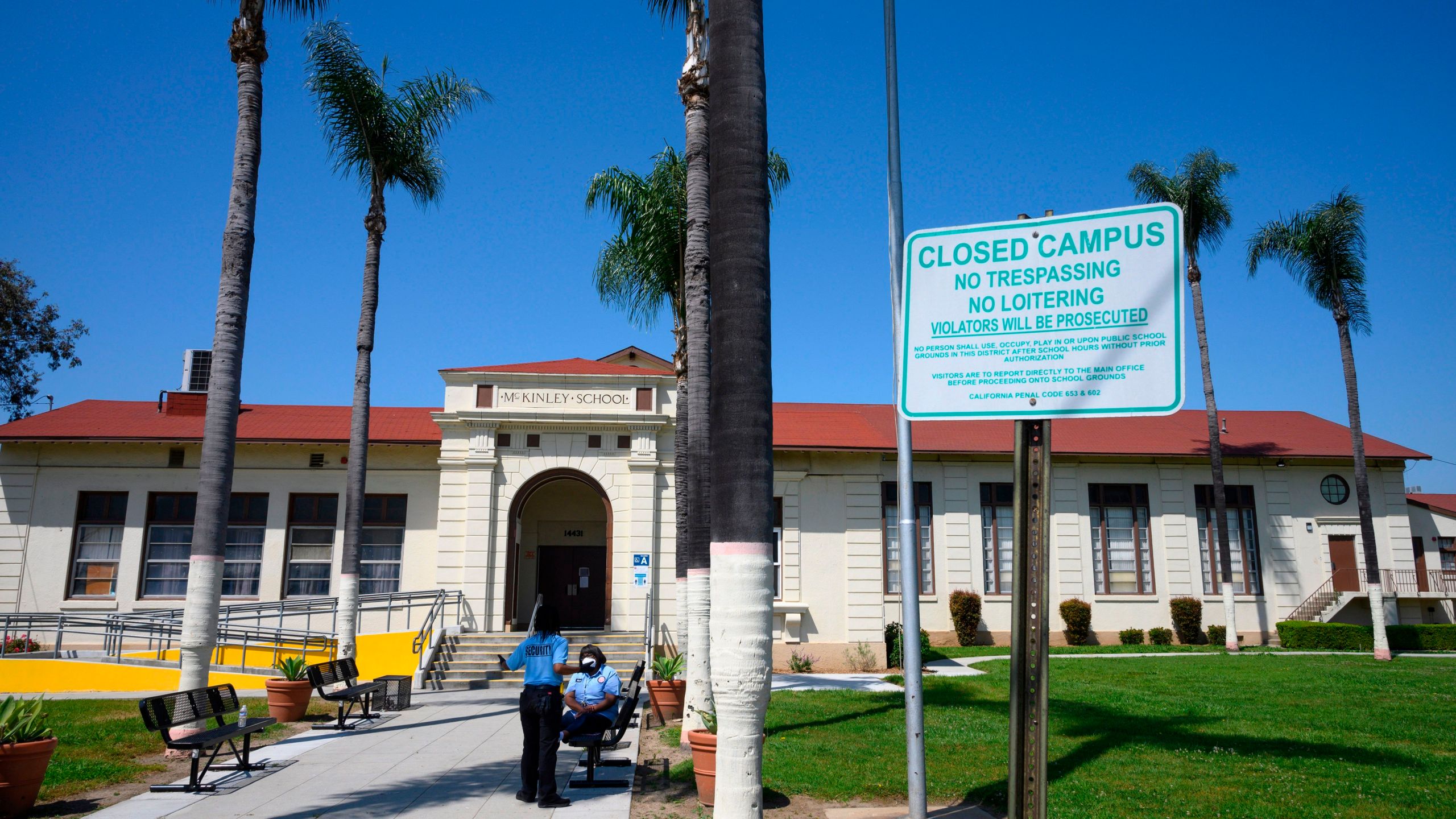 Two security guards talk on the campus of the closed McKinley School, part of the Los Angeles Unified School District system, in Compton on April 28, 2020. (ROBYN BECK/AFP via Getty Images)