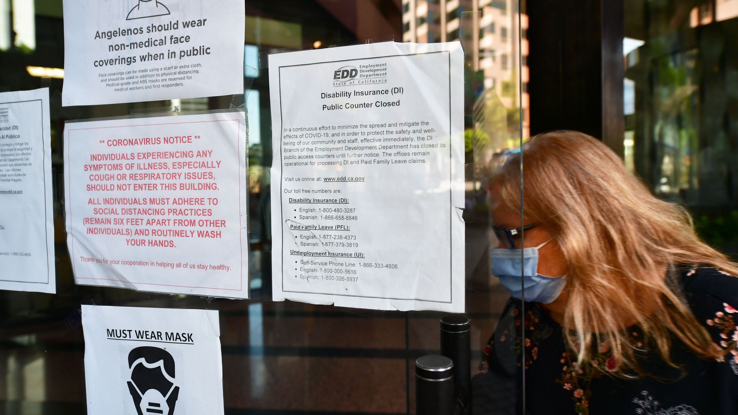 A woman wearing a face mask enters a building where the Employment Development Department has its offices in Los Angeles on May 4, 2020. (FREDERIC J. BROWN/AFP via Getty Images)