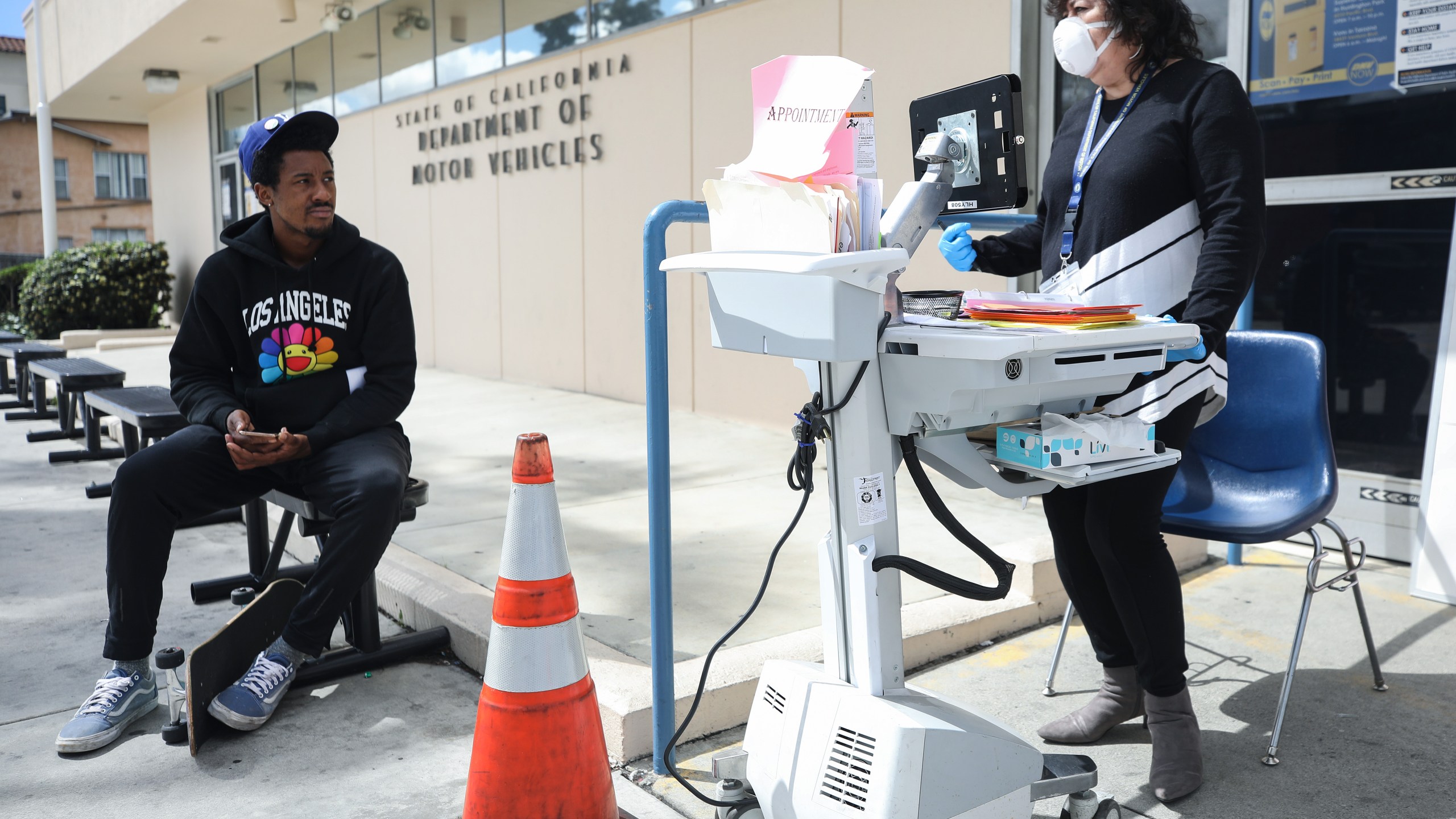 A Department of Motor Vehicles worker speaks with a man who did not have an appointment at an appointment desk in front of the DMV building, with a cone used to implement social distancing, on March 23, 2020 in Los Angeles. (Mario Tama/Getty Images)