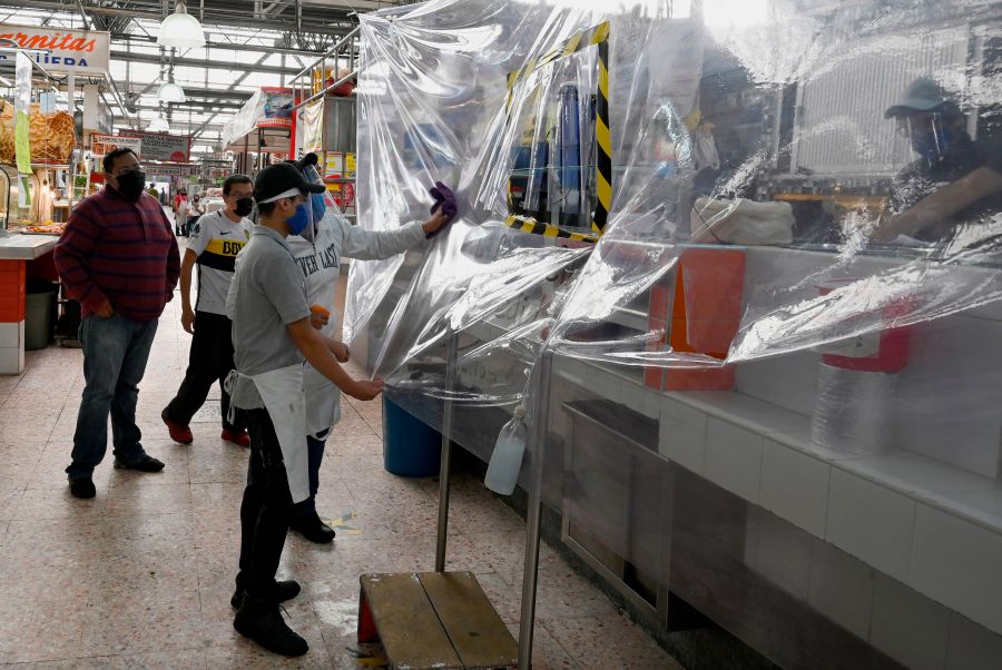 Two workers clean the plastic protection of a store to prevent the spread of COVID-19 at the Martinez de la Torre Market in Mexico City on May 28, 2020. (ALFREDO ESTRELLA/AFP via Getty Images)