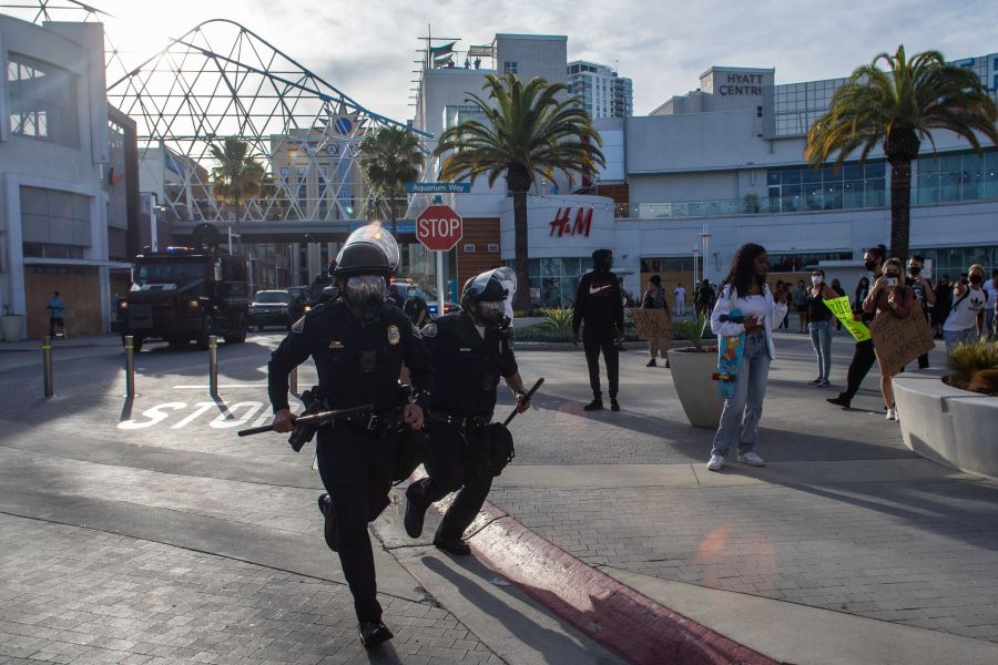 Police officers run in downtown Long Beach on May 31, 2020 during a protest against the death of George Floyd. (Apu GOMES / AFP) (Photo by APU GOMES/AFP via Getty Images)