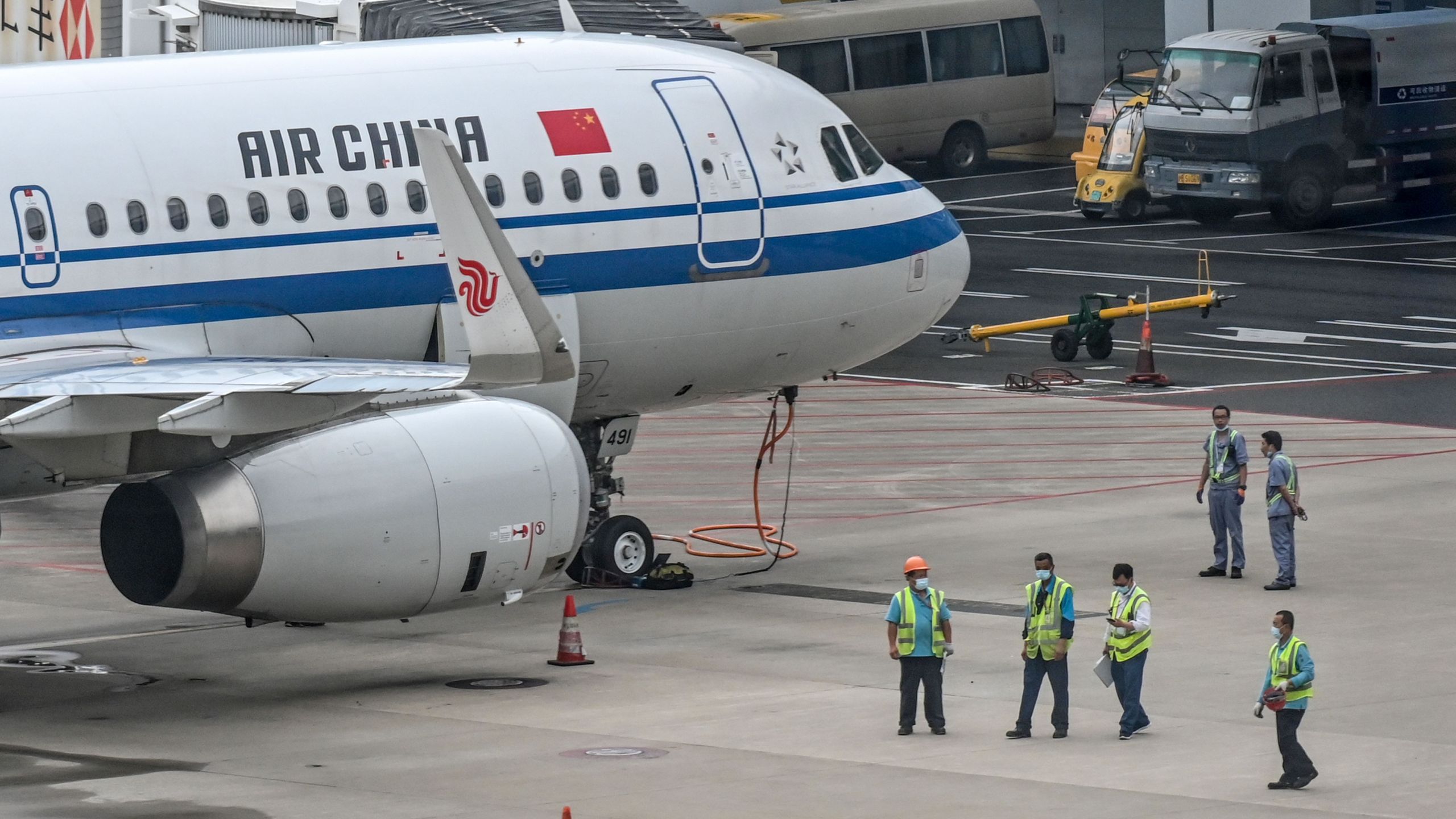 Employees work next to an Air China plane following preventive procedures against the spread of the COVID-19 coronavirus in Pudong International Airport in Shanghai on June 11, 2020. (HECTOR RETAMAL/AFP via Getty Images)