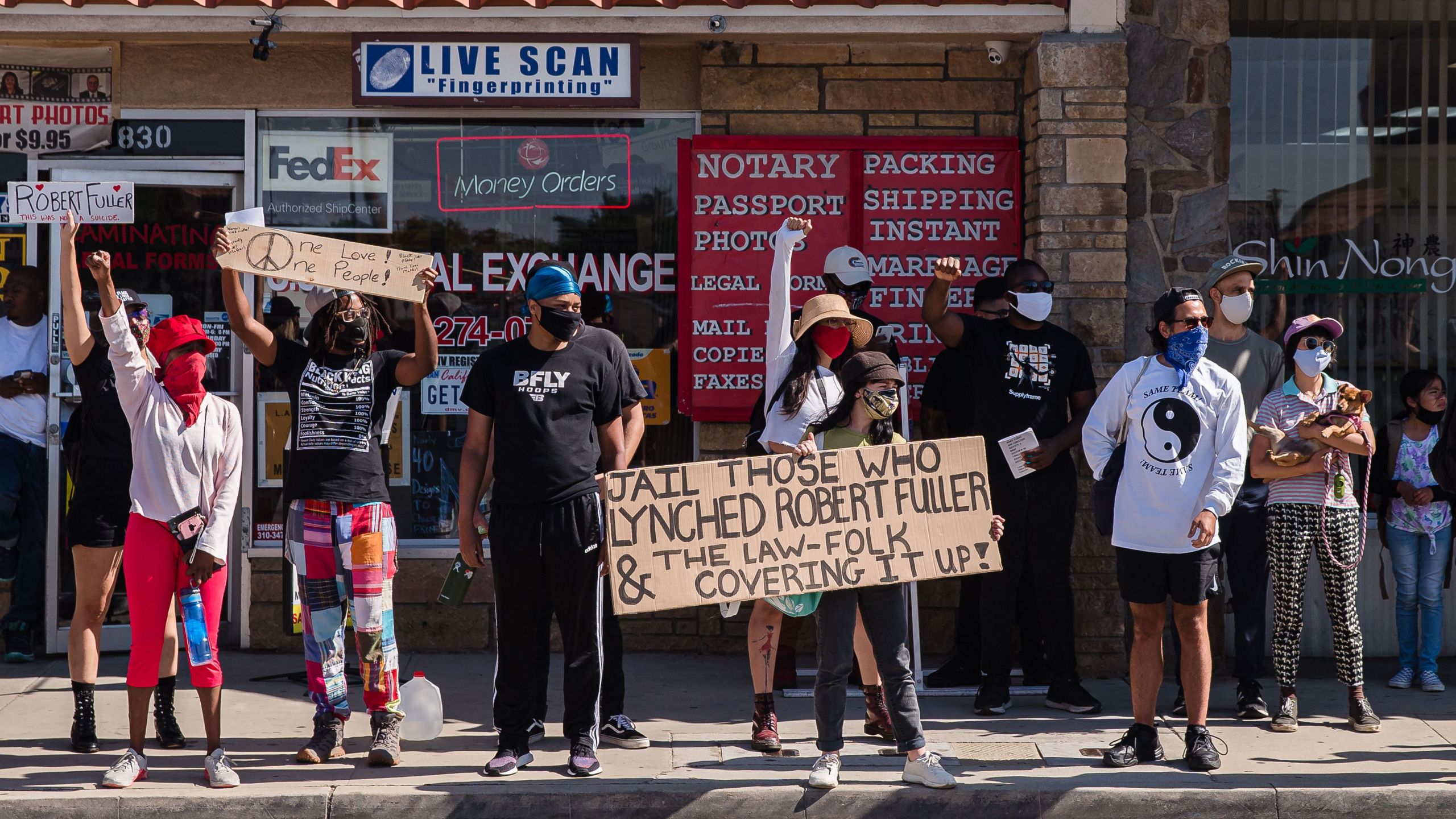 Protesters hold up placards as they gather on Palmdale Boulevard on June 16, 2020, demanding justice for Robert Fuller, a young black man who was found hanging from a tree in Palmdale. (Ariana Drehsler / AFP / Getty Images)