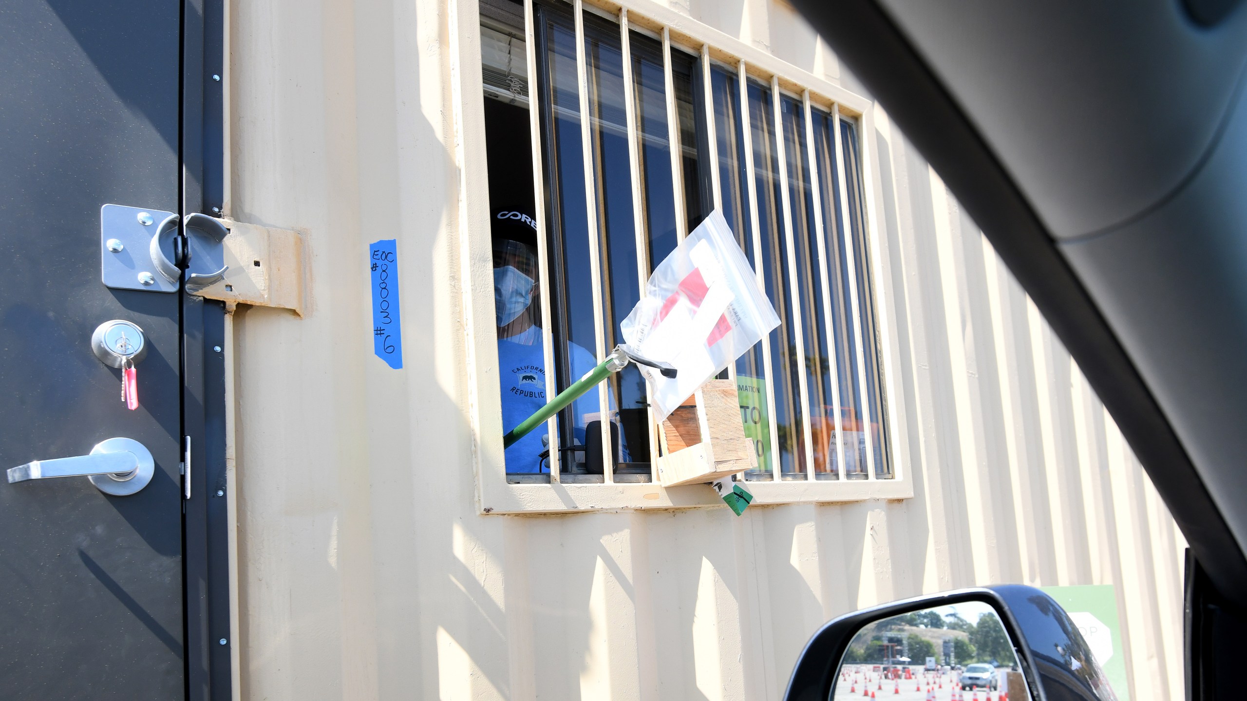 A worker uses a grabber tool to hand over a COVID-19 testing kit at Dodger Stadium on May 28, 2020. (Harry How/Getty Images)