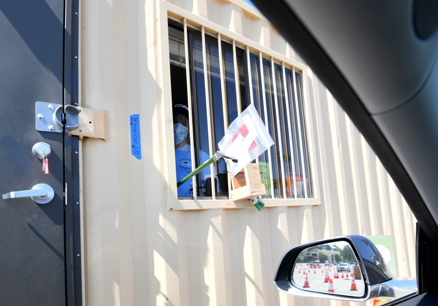 A worker uses a grabber tool to hand over a COVID-19 testing kit at Dodger Stadium on May 28, 2020. (Harry How/Getty Images)