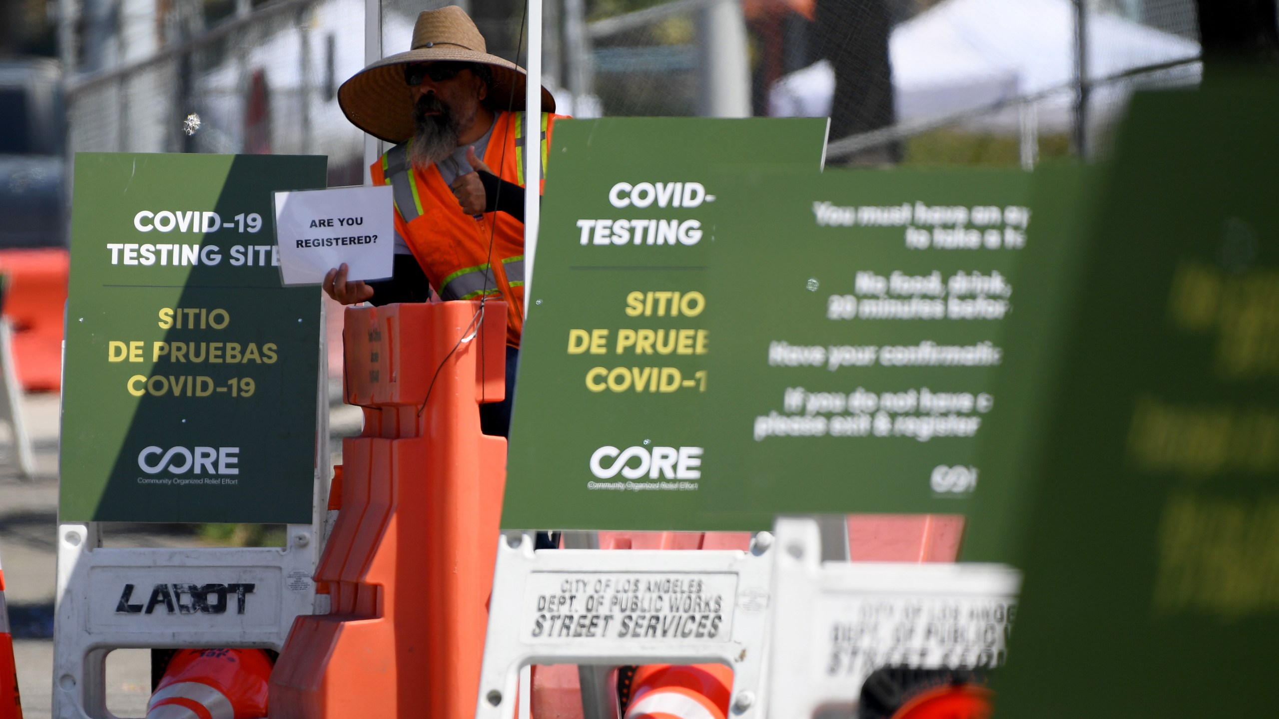 A worker holds up a sign asking for registration at a COVID-19 testing site at Dodger Stadium on May 28, 2020. (Harry How/Getty Images)