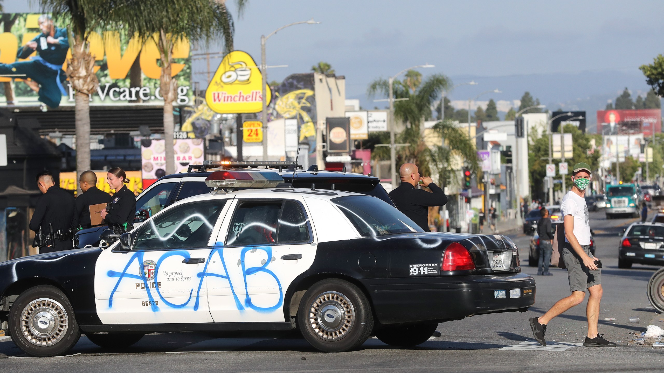 A man walks past a defaced LAPD vehicle in the Fairfax District, an area damaged during civil unrest, following demonstrations in response to George Floyd’s death on May 31, 2020, in Los Angeles. (Mario Tama/Getty Images)