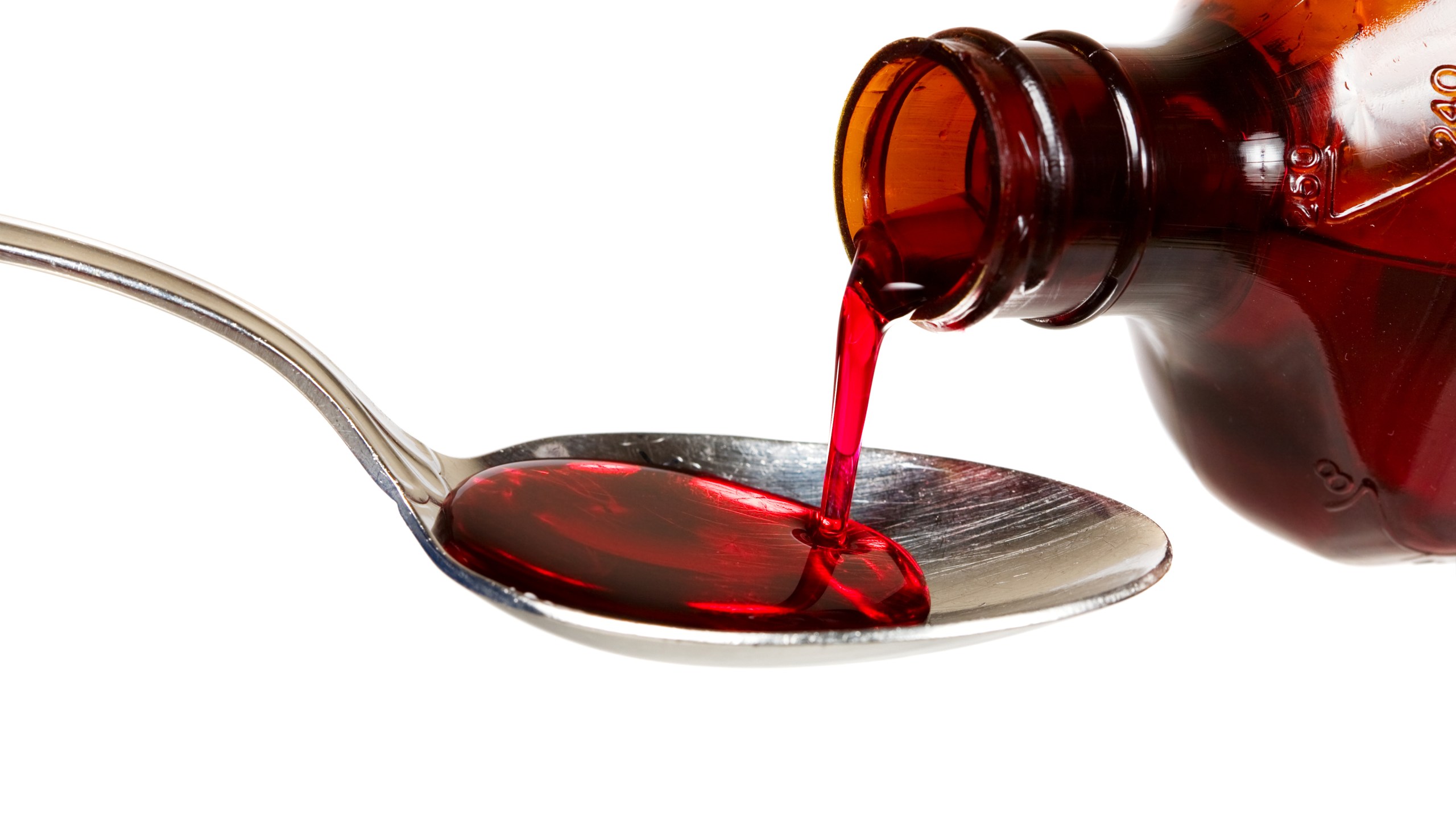 A bottle of cold medicine poured into a spoon (iStock/Getty Images Plus)