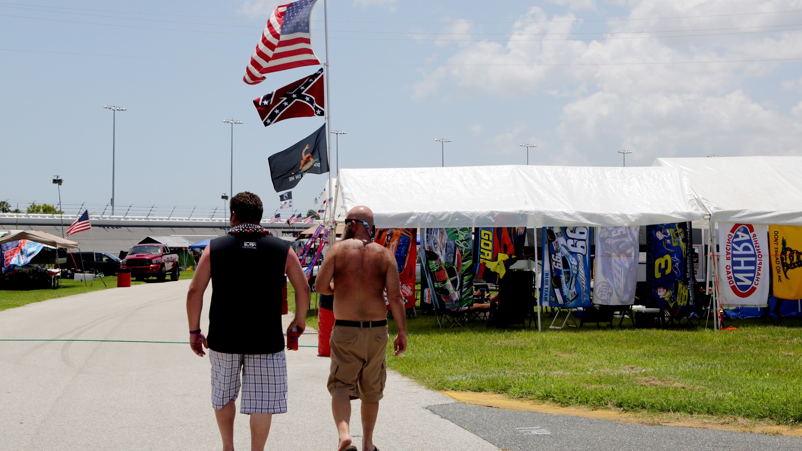 Fans walk past an American flag and a Confederate flag in the camp ground before practice for the NASCAR XFINITY Series Subway Firecracker 250 at Daytona International Speedway on July 3, 2015 in Daytona Beach, Florida. (Photo by Jerry Markland/Getty Images)