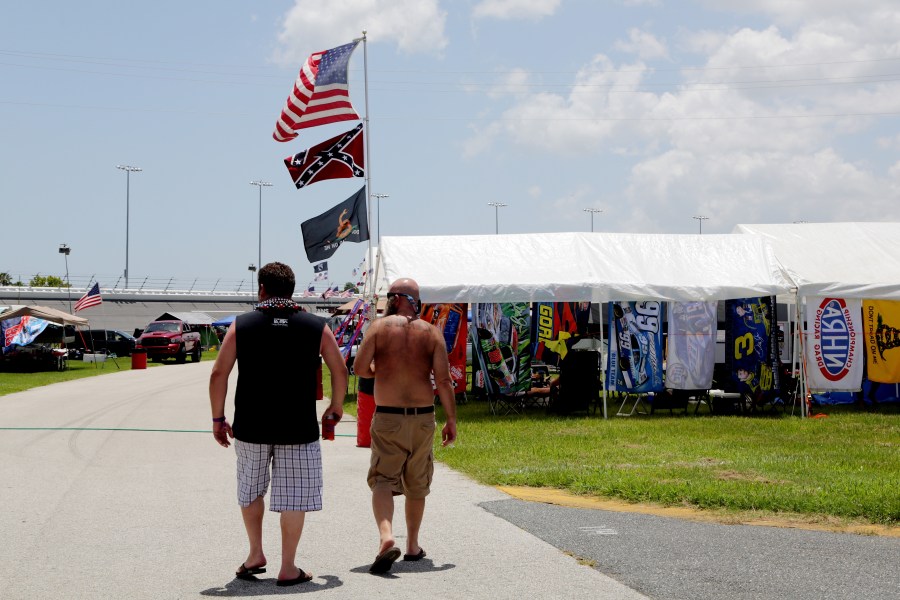 Fans walk past an American flag and a Confederate flag in the camp ground before practice for the NASCAR XFINITY Series Subway Firecracker 250 at Daytona International Speedway on July 3, 2015 in Daytona Beach, Florida. (Photo by Jerry Markland/Getty Images)