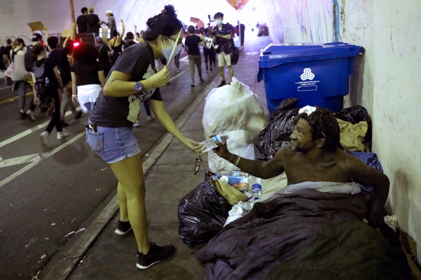 A protester hands Isaac D., who is homeless, a bottle of water in the 2nd Street tunnel on June 4 in downtown Los Angeles.(Gary Coronado/Los Angeles Times)