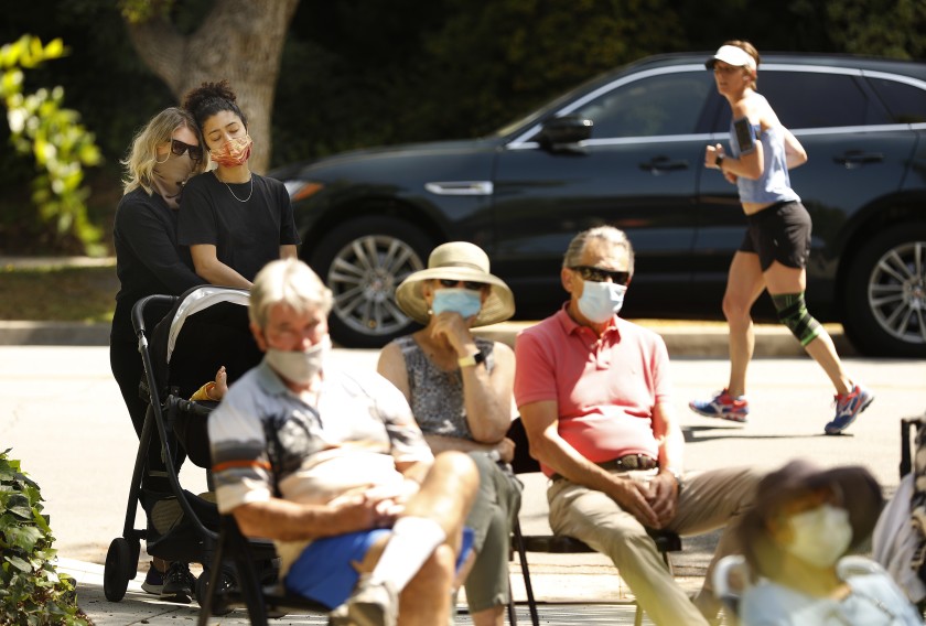 A socially distanced and mask-wearing crowd gathers on the lawn of Catherine and Jonathan Karoly’s home in Pasadena to hear them play music.(Christina House / Los Angeles Times)