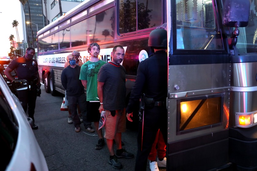 Protesters are loaded onto a bus after being arrested for violating curfew along Sunset Boulevard in Hollywood on June 1, 2020. (Gary Coronado / Los Angeles Times)