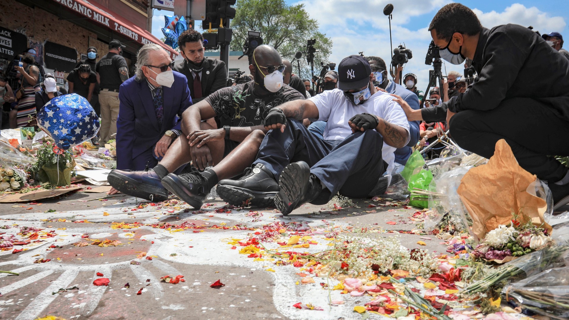 FILE - in this June 1, 2020 file photo, an emotional Terrence Floyd, second from right, is comforted as he sits at the spot at the intersection of 38th Street and Chicago Avenue, Minneapolis, Minn., where his brother George Floyd, encountered police and died while in their custody. (AP Photo/Bebeto Matthews File)