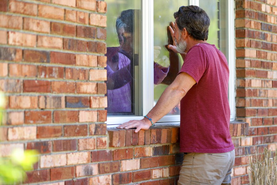 Jack Campise talks with his mother, Beverly Kearns, through her apartment window at the Kimberly Hall North nursing home in Windsor, Conn. The coronavirus has had no regard for health care quality or ratings as it has swept through nursing homes around the world, killing efficiently even in highly rated care centers. Preliminary research indicates the numbers of nursing home residents testing positive for the coronavirus and dying from COVID-19 are linked to location and population density — not care quality ratings. (AP Photo/Chris Ehrmann)