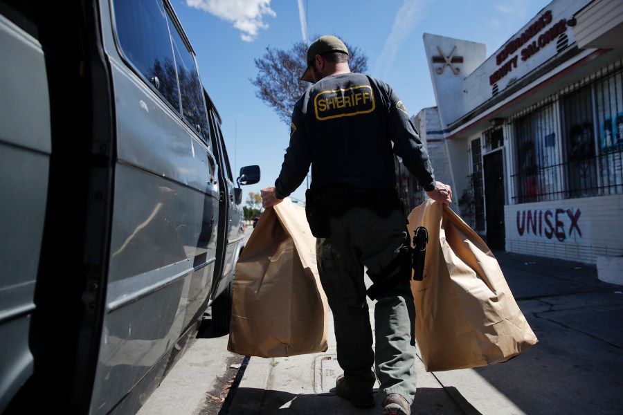 In this March 15, 2018 file photo, an undercover Los Angeles County sheriff's deputy loads two evidence bags into a van after raiding an illegal marijuana dispensary in Compton, one of many California cities where recreational marijuana use remains illegal. (AP Photo/Jae C. Hong, File)