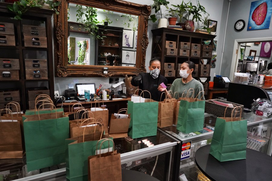 In this April 16, 2020, file photo, budtenders wearing protective masks prepare orders for customers to pick up at the Higher Path cannabis dispensary in the Sherman Oaks. (AP Photo/Richard Vogel, File)