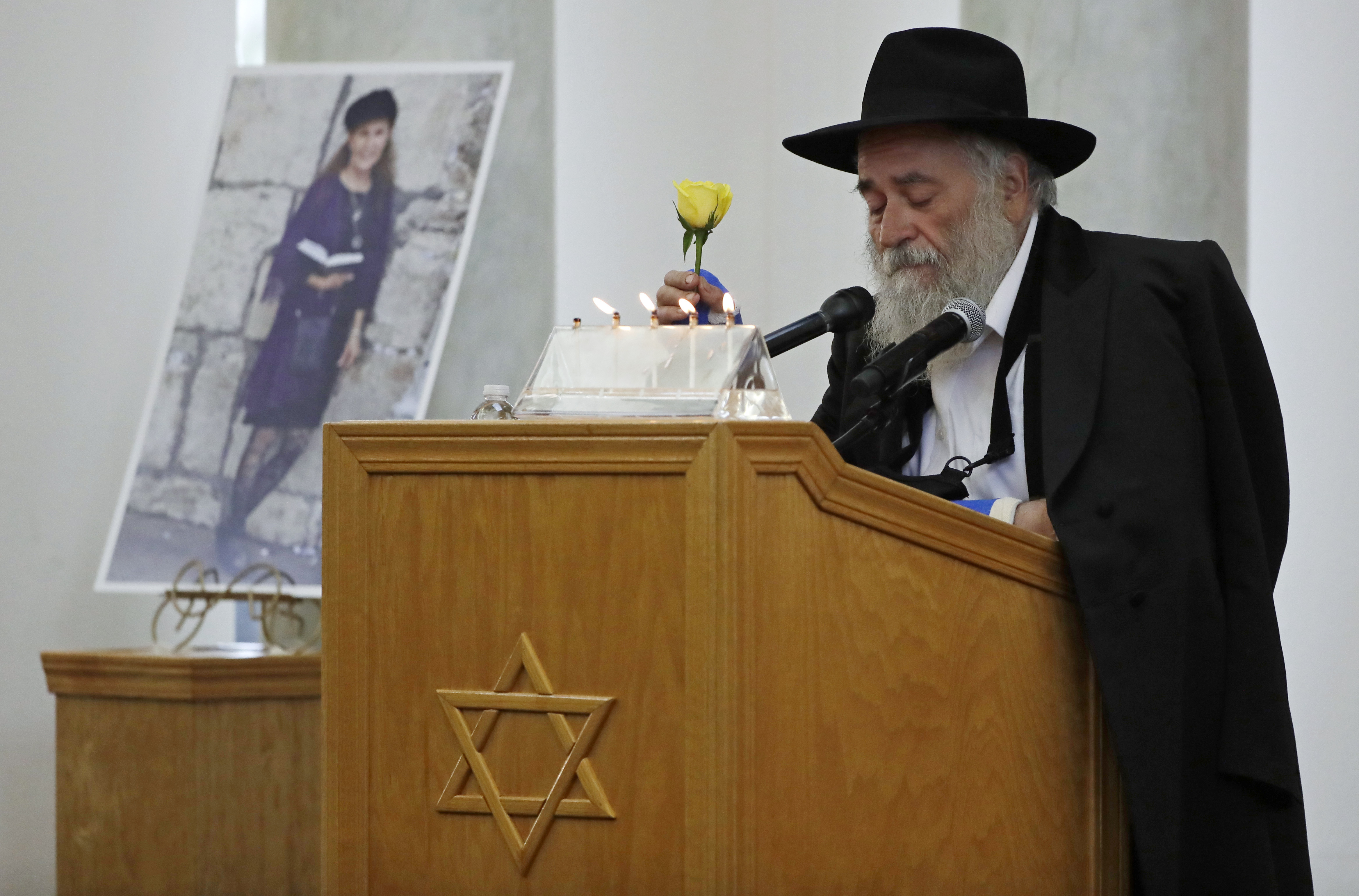 Yisroel Goldstein, Rabbi of Chabad of Poway, holds a yellow rose as he speaks at the funeral for Lori Gilbert-Kaye, who is pictured at left, in Poway on April 29, 2019. (AP Photo/Gregory Bull, File)