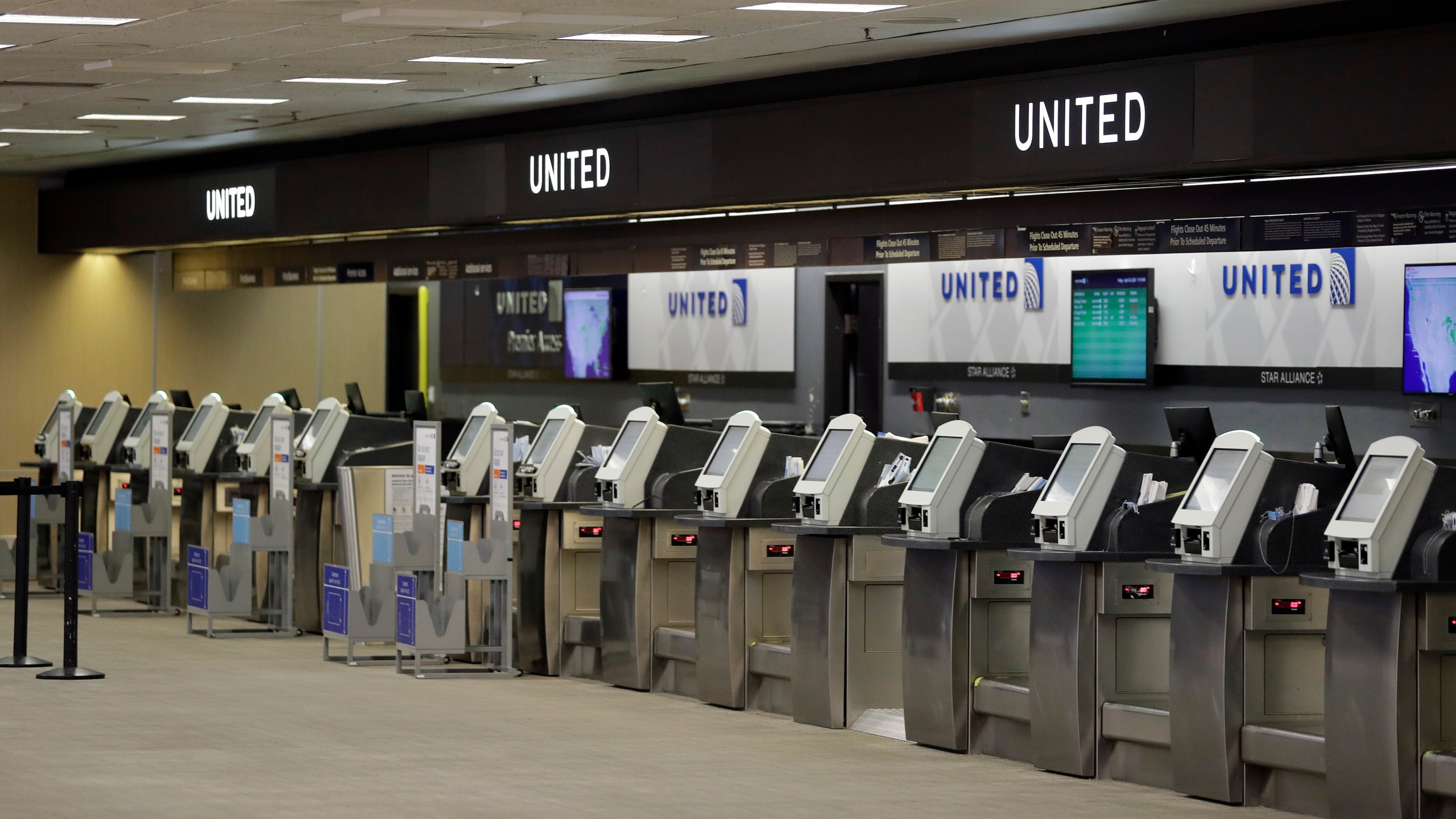 In this April 24, 2020 file photo, empty United Airlines ticket machines are shown at the Tampa International Airport in Tampa, Fla. United United Airlines will send layoff warnings to 36,000 employees - nearly half its U.S. staff - in the clearest signal yet of how deeply the virus outbreak is hurting the airline industry. (AP Photo/Chris O'Meara, File)