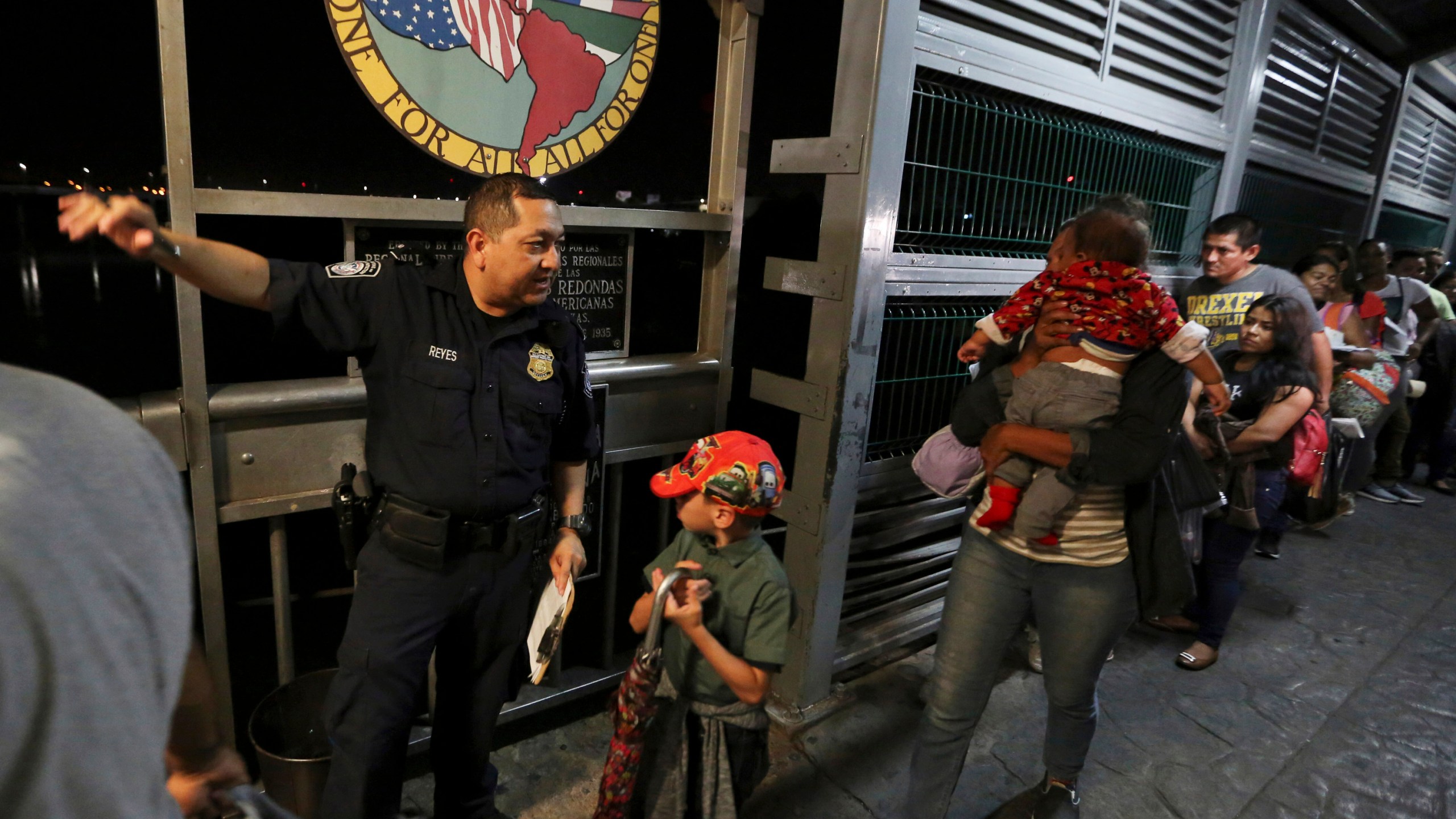 In this Sept. 17, 2019, file photo, a U.S. Customs and Border Protection officer gives instructions to migrants who are on their way to apply for asylum in the United States, on International Bridge 1 as they depart Nuevo Laredo, Mexico. (AP Photo/Fernando Llano, File)