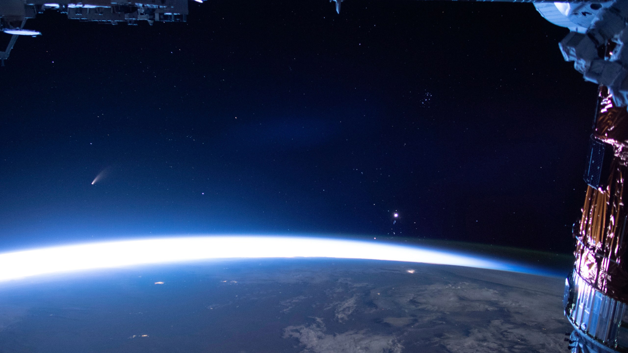 In this image released by NASA, Comet Neowise, left, is seen in the eastern horizon above Earth in this image taken from the International Space Station on Sunday, July 5, 2020. (NASA via AP)