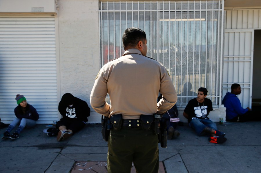 A Los Angeles County Sheriff's deputy keeps watch on a group of people apprehended at an illegal marijuana dispensary in Compton in this March 15, 2018, file photo. (Jae C. Hong / Associated Press)