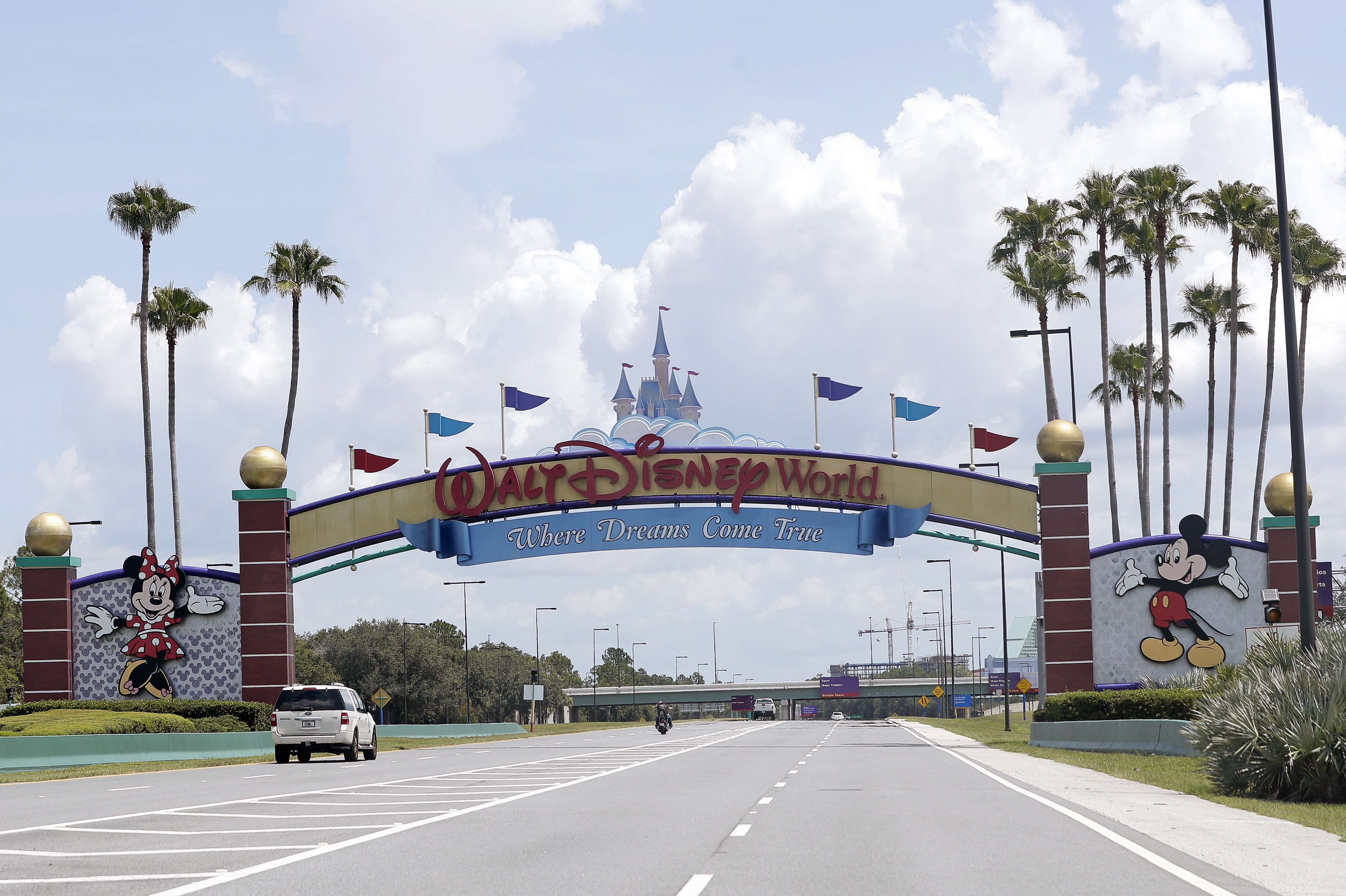 Cars drive under a sign greeting visitors near the entrance to Walt Disney World, in Lake Buena Vista, Florida on July 2, 2020. (AP Photo/John Raoux, File)