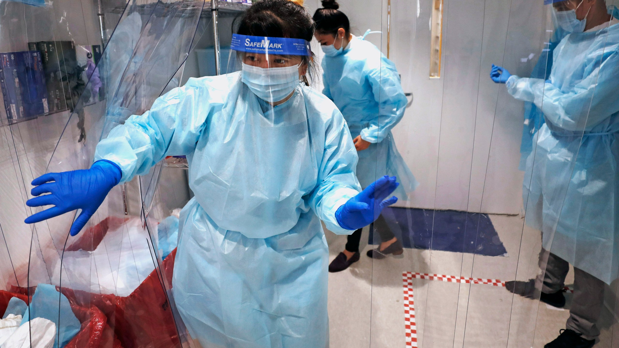 Lena Landaverde, assistant director of the Precision Diagnostics Center, heads to the new COVID-19, on-campus testing labs after donning personal protective equipment, Thursday, July 23, 2020, at Boston University in Boston. (AP Photo/Charles Krupa)