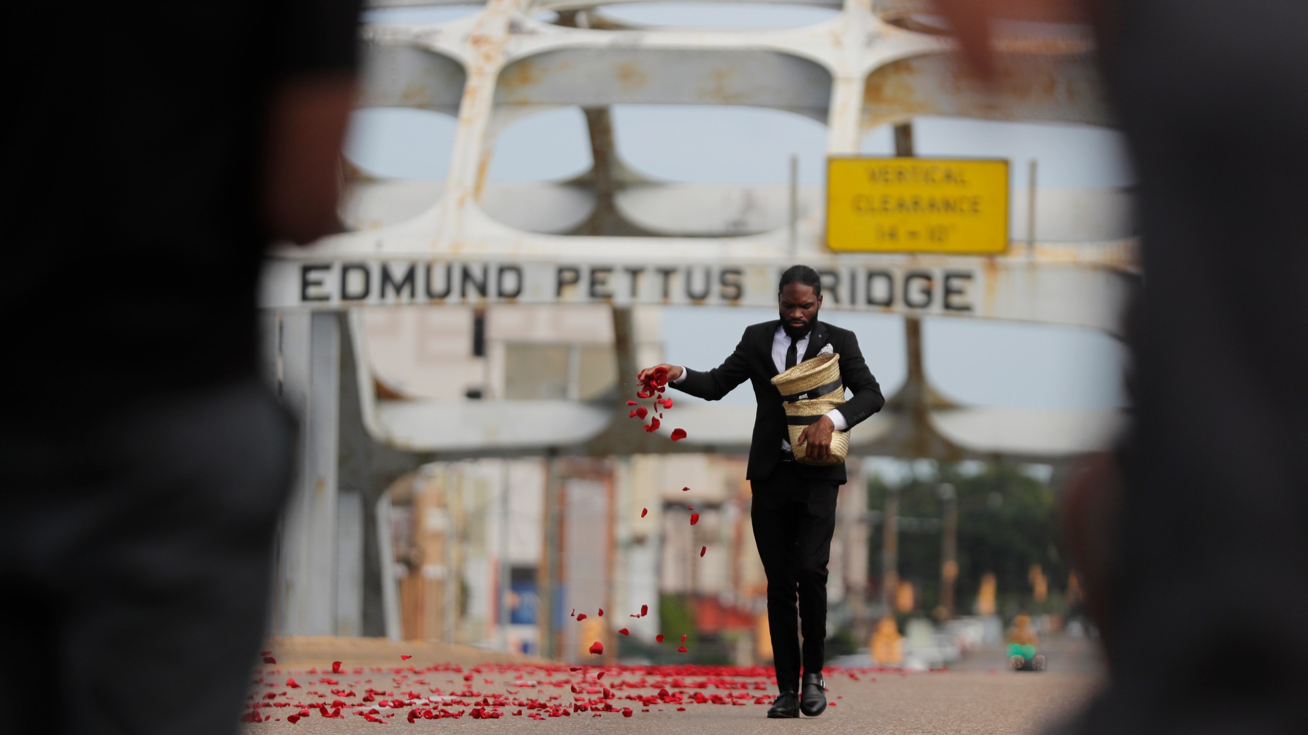 A man places flower petals on the Edmund Pettus Bridge ahead of Rep. John Lewis' casket crossing during a memorial service for Lewis, Sunday, July 26, 2020, in Selma, Ala. (AP Photo/Brynn Anderson)