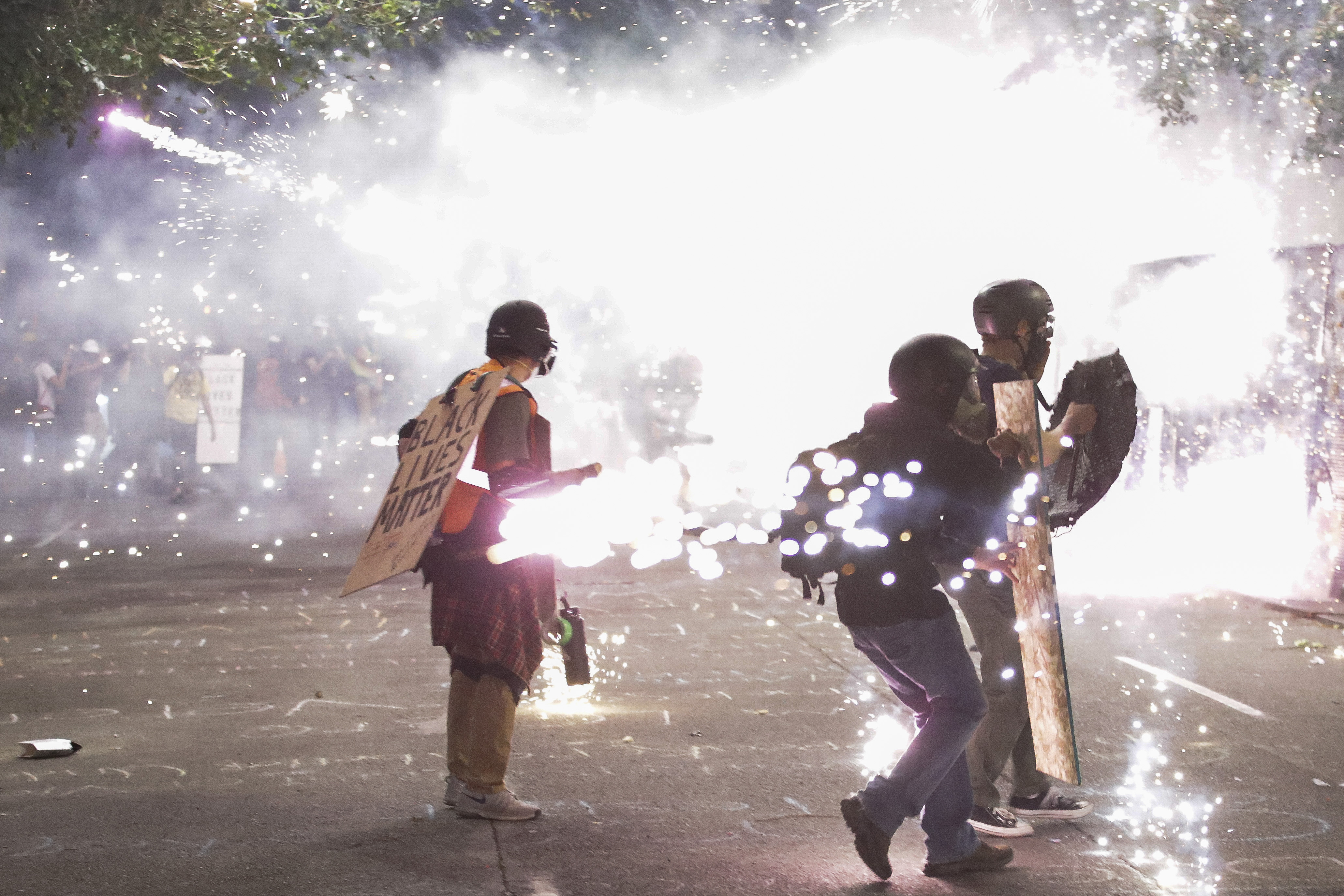 Protesters walk away from crowd control munitions launched by federal officers during a Black Lives Matter protest at the Mark O. Hatfield United States Courthouse Sunday, July 26, 2020, in Portland, Ore. (AP Photo/Marcio Jose Sanchez)