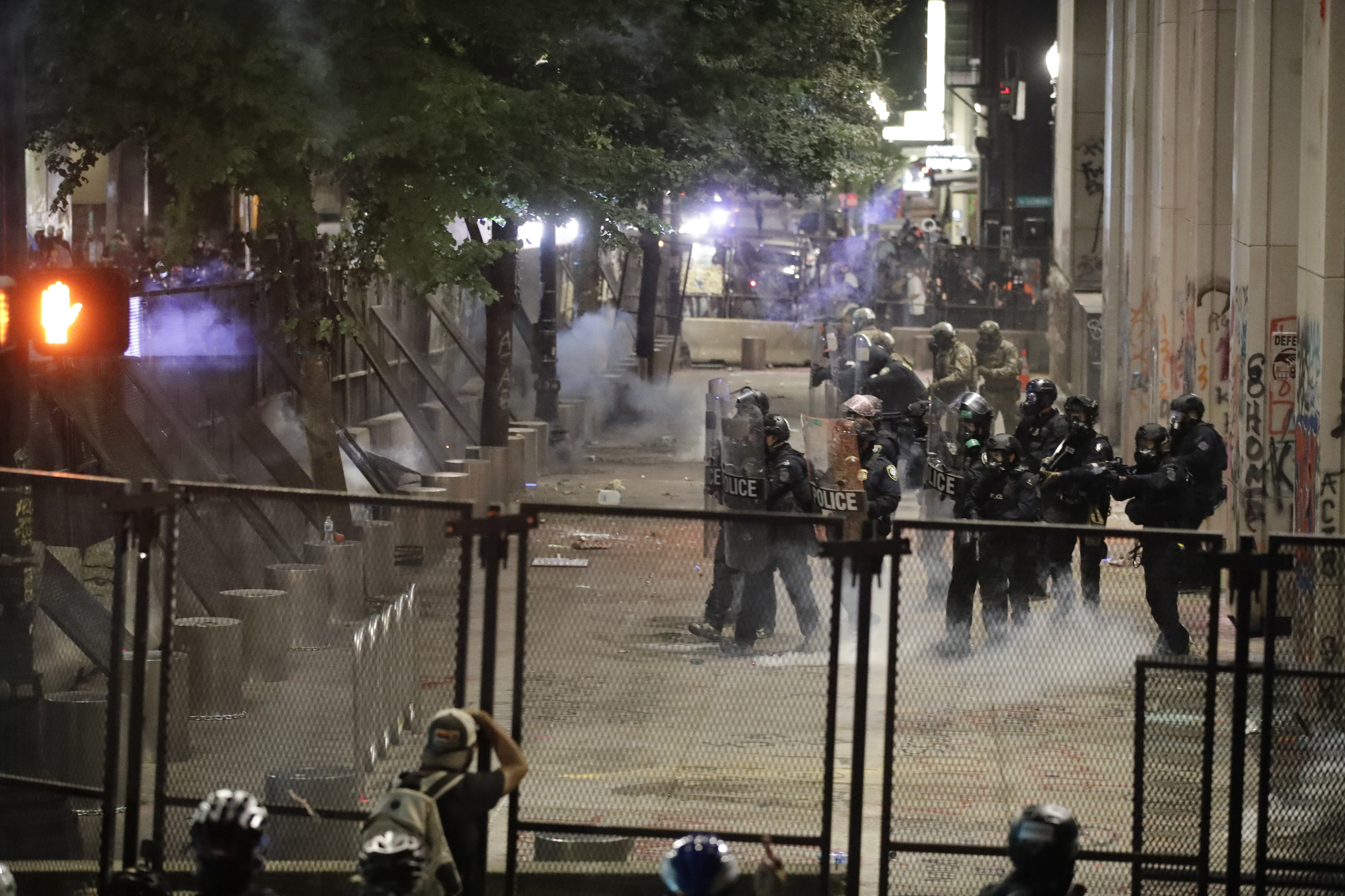 Federal officers walk out in formation to launch tear gas at demonstrators during a Black Lives Matter protest at the Mark O. Hatfield United States Courthouse Sunday, July 26, 2020, in Portland, Ore. (AP Photo/Marcio Jose Sanchez)