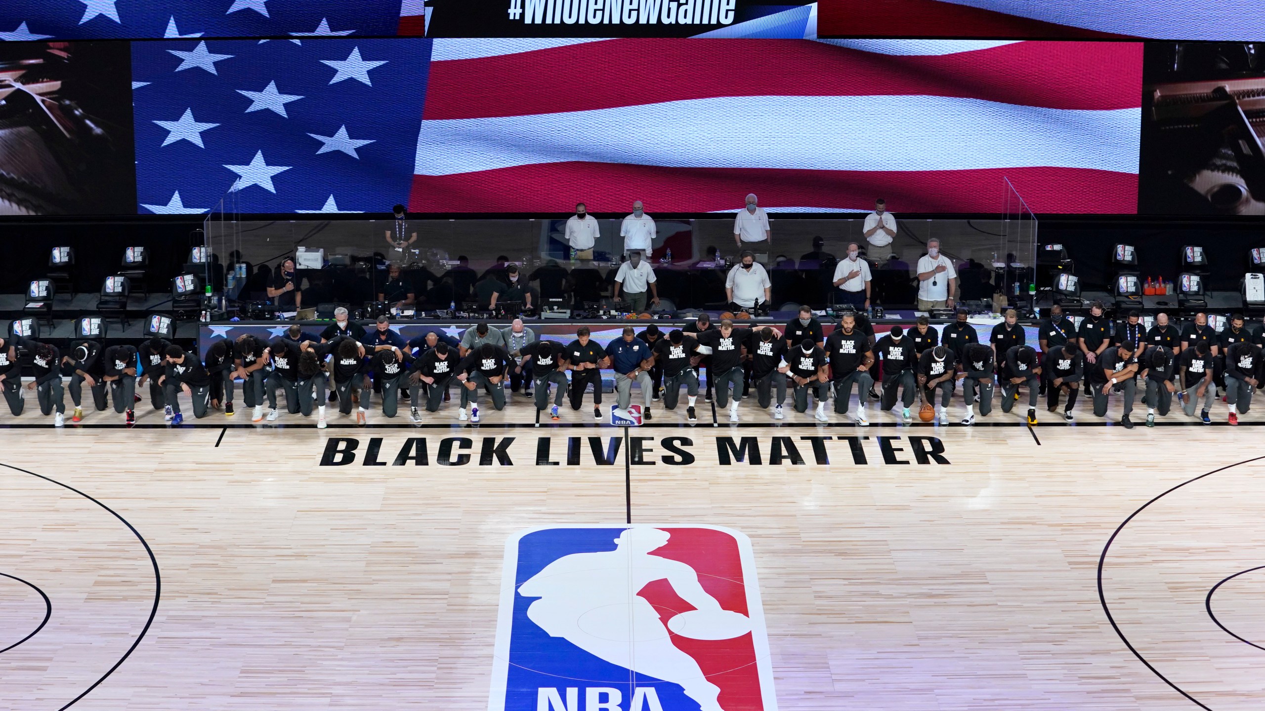 Members of the New Orleans Pelicans and Utah Jazz kneel together around the Black Lives Matter logo on the court during the national anthem before the start of an NBA basketball game on July 30, 2020, in Lake Buena Vista, Fla. (AP Photo/Ashley Landis, Pool)