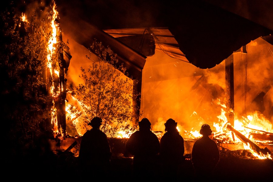 Firefighters look on as a structure burns during the Kincade Fire off Highway 128, east of Healdsburg, California on Oct. 29, 2019. Philip Pacheco/AFP via Getty Images)