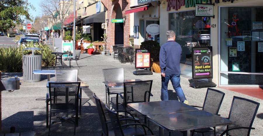 A man glances strides along a quiet sidewalk in downtown Palo Alto in Santa Clara County on March 12, 2020. (GLENN CHAPMAN/AFP via Getty Images)