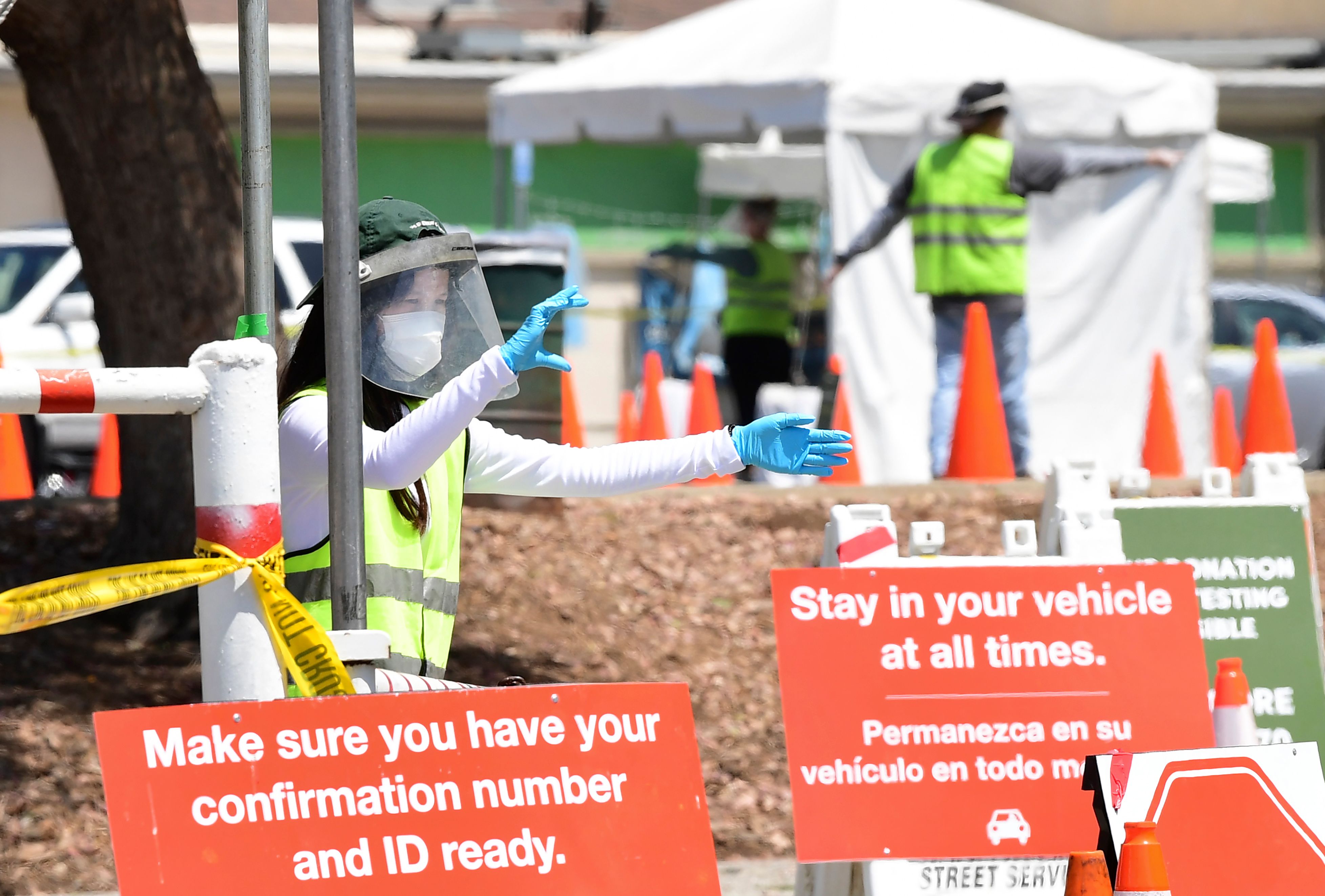 COVID-19 test site volunteers wearing personal protective equipment assist drivers arriving at a coronavirus test site in Los Angeles on July 10, 2020. (Frederic J. Brown / AFP / Getty Images)