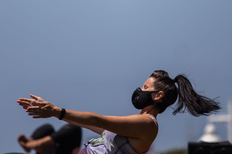 A woman wearing a facemask practices yoga at Bluff park in Long Beach on July 14, 2020. San Diego County is set to consider a proposal that could make it easier for fitness centers to operate in county parks.(APU GOMES/AFP via Getty Images)