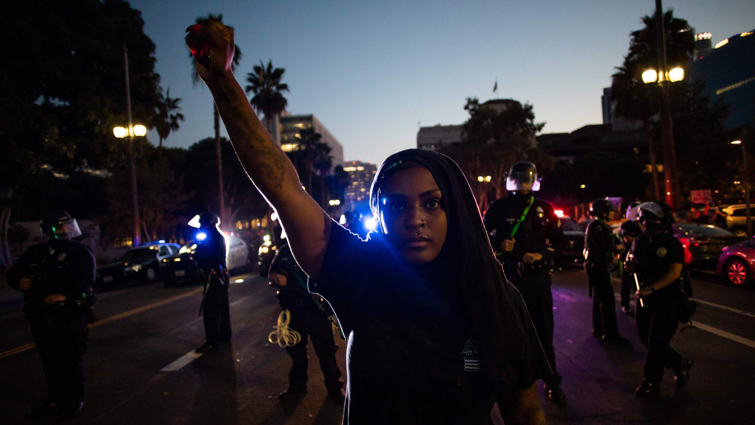 A woman holds up her fist in front of a row of police officers during a protest demanding justice for George Floyd, Breonna Taylor and also in solidarity with Portland's protests, in downtown Los Angeles, on July 25, 2020. (APU GOMES/AFP via Getty Images)