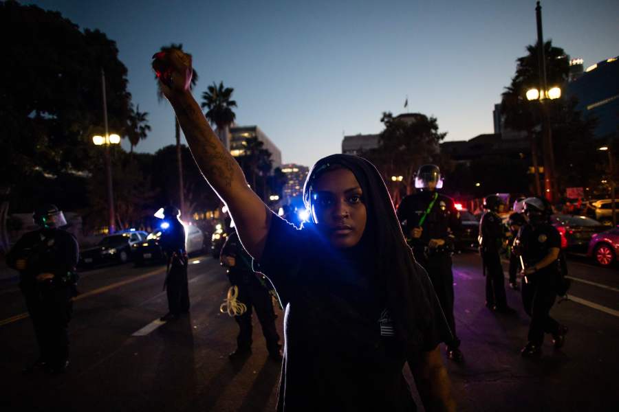 A woman holds up her fist in front of a row of police officers during a protest demanding justice for George Floyd, Breonna Taylor and also in solidarity with Portland's protests, in downtown Los Angeles, on July 25, 2020. (APU GOMES/AFP via Getty Images)