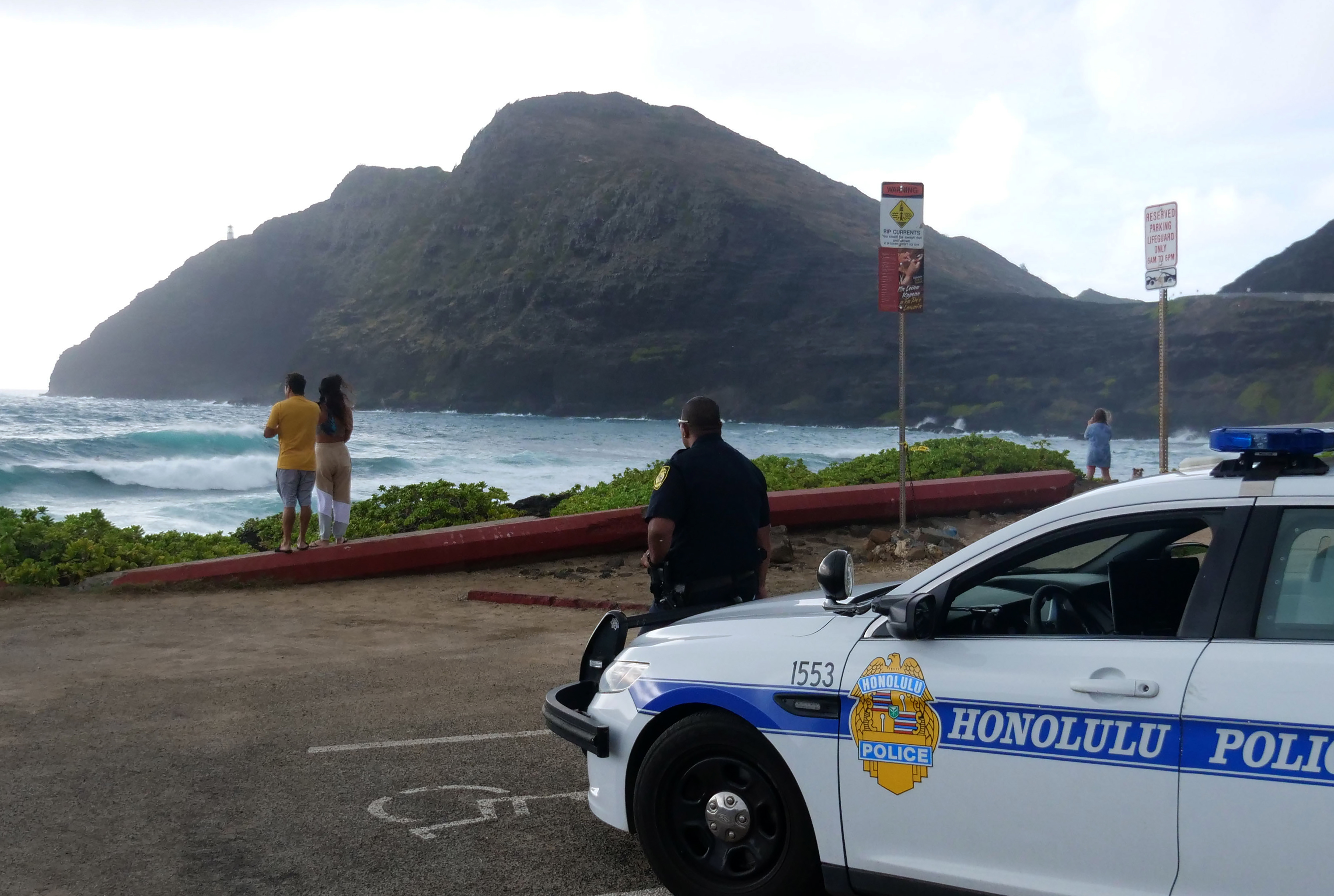 Police wait for people to return to their cars before closing the beach parking lot in preparation for Hurricane Douglas, in Honolulu, Hawaii, on July 26, 2020. (RONEN ZILBERMAN/AFP via Getty Images)