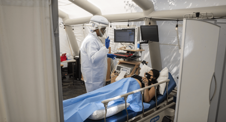 Nurse Janil Wise, left, screens patient Sarah Bodle, who is pregnant and was exposed to a person with COVID-19, in the OB triage tent at Providence Holy Cross Medical Center in Mission Hills.(Brian van der Brug / Los Angeles Times)