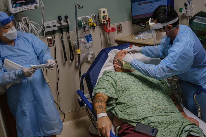 RN Arnold Garcia collects a sample for a coronavirus test from Michael Weiss after he was admitted with possible COVID-19 symptoms at Sharp Chula Vista Medical Center in Chula Vista, Calif., on April 10.(Marcus Yam/Los Angeles Times)