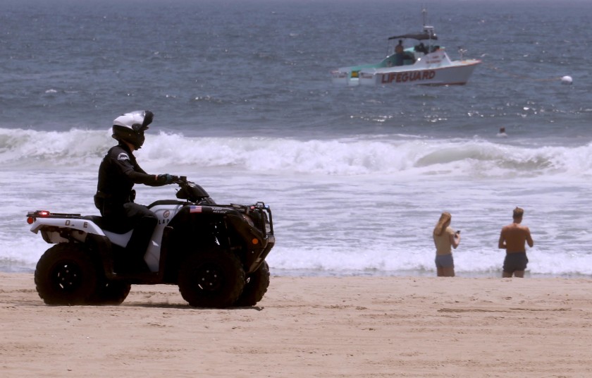 A police officer and a lifeguard boat patrol the shoreline in Venice Beach on July 5, 2020. Even though the beach was closed over the weekend, a few still made their way to the shore.(Genaro Molina / Los Angeles Times)