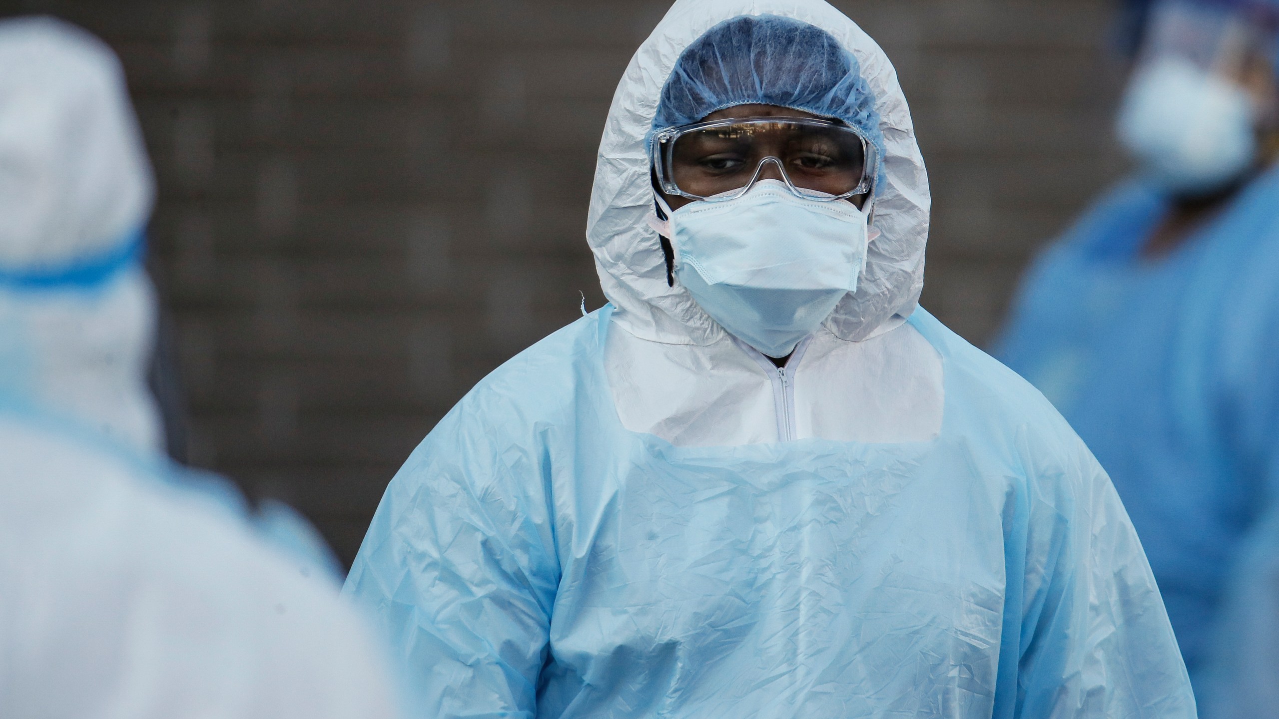 A medical worker wearing personal protective equipment pauses after wheeling a body to a refrigerated trailer serving as a makeshift morgue at Wyckoff Heights Medical Center on April 6, 2020, in New York. (AP Photo/John Minchillo)