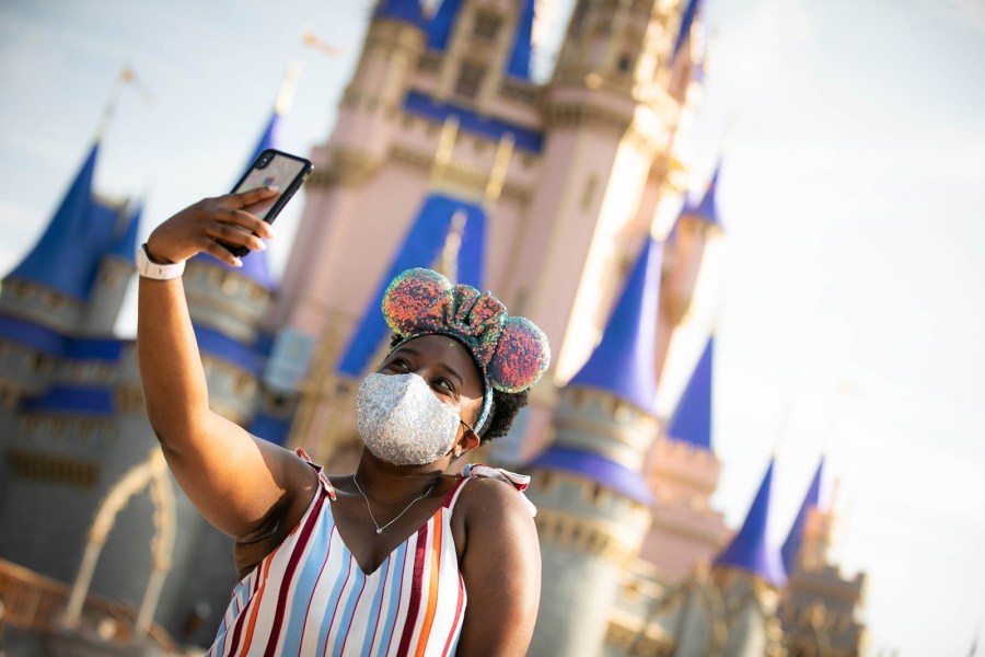 In this handout photo provided by Walt Disney World Resort, a guest stops to take a selfie at Magic Kingdom Park at Walt Disney World Resort on July 11, 2020 in Lake Buena Vista, Florida. July 11, 2020 is the first day of the phased reopening. (Olga Thompson/Walt Disney World Resort via Getty Images)