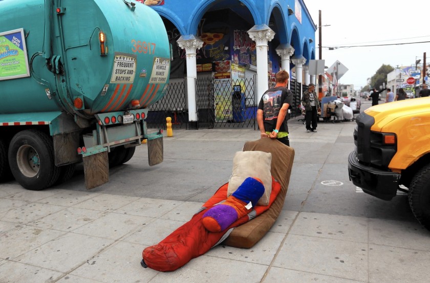 A man drags his bedding after a sweep of homeless encampments on the Venice Beach boardwalk on June 26, 2020. (Genaro Molina / Los Angeles Times)